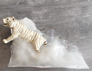 Photo d'un tigre blanc en jouet pris dans la glace pour illustré l'article intitulé : Les explorateurs de glace ! Une activité pour se rafraîchir avec les enfants pendant la canicule